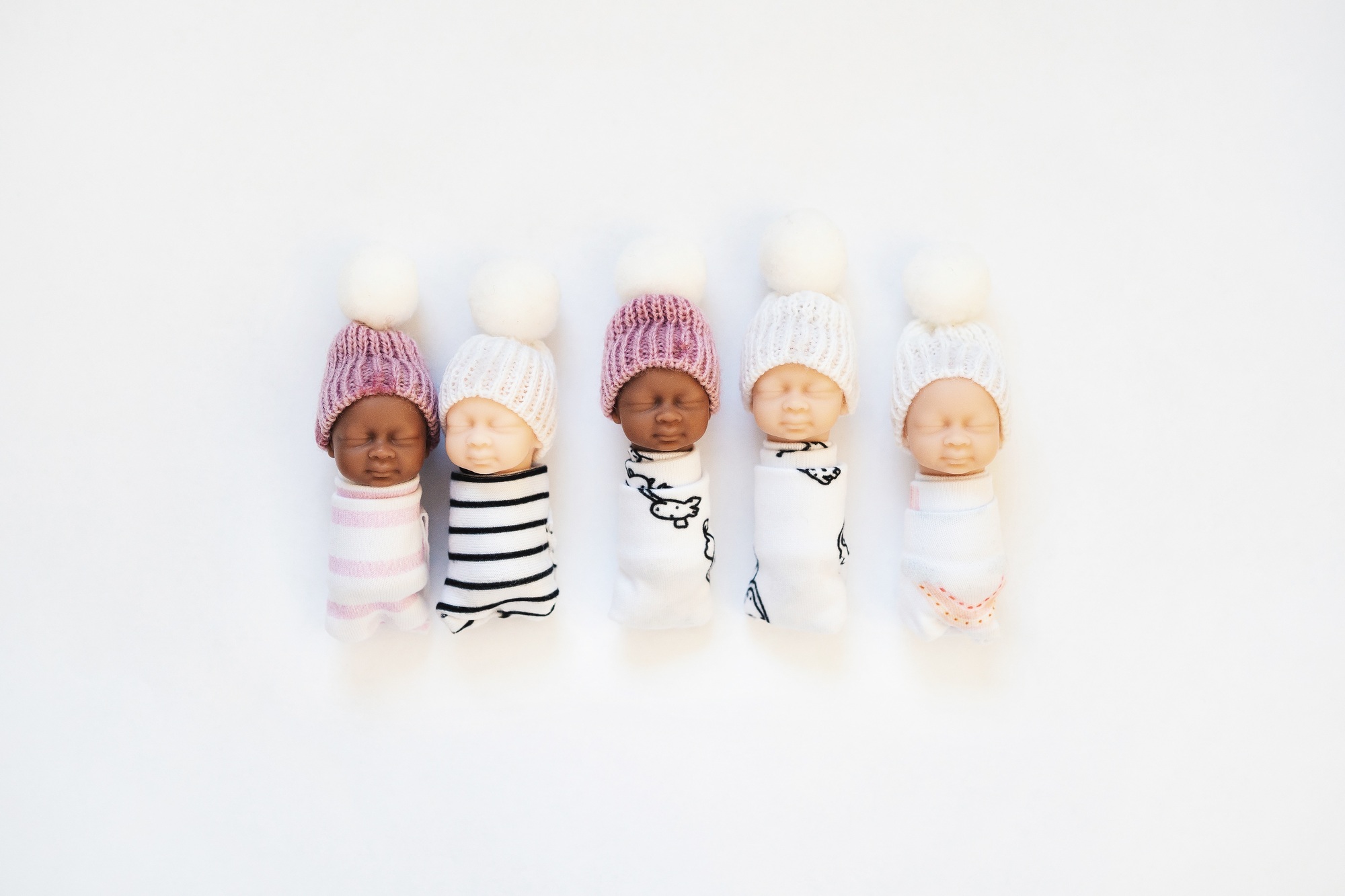 Newborn babies toys with different skin tones on white background